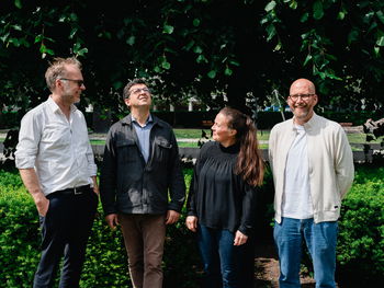 Fire musikere står foran en hekk